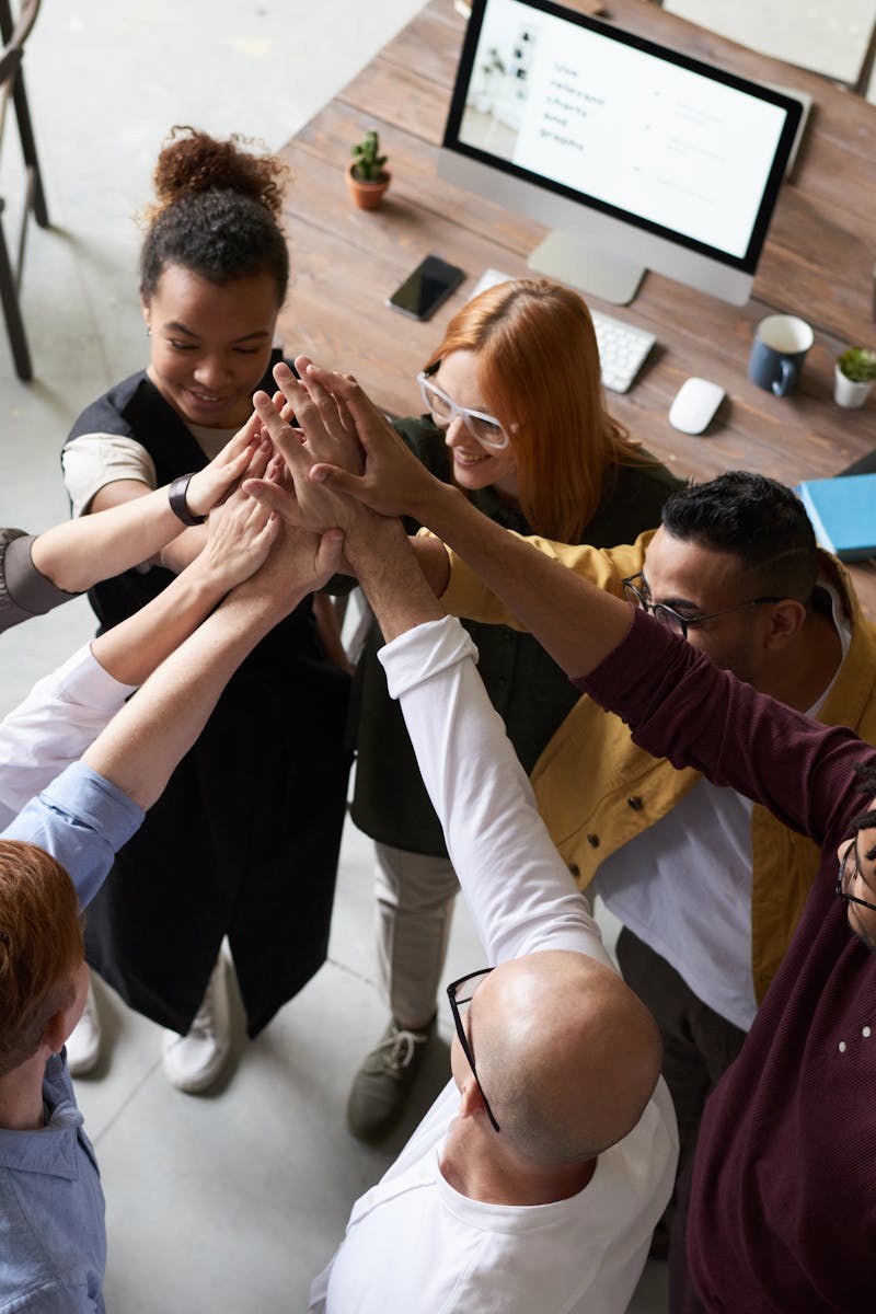 A diverse group of colleagues giving a high five during a corporate meeting indoors.